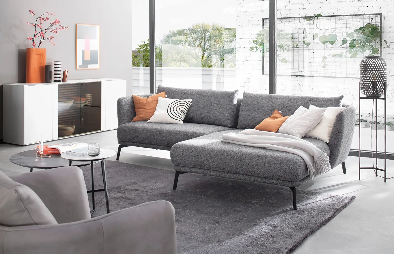 Graues Sofa mit Longchair in Raum mit wand-großen Fenstern